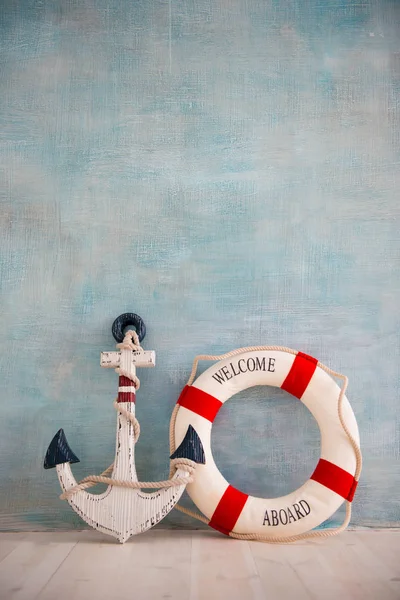 A composition on a sea theme with an anchor and lifebuoy on a blue wall — Stock Photo, Image