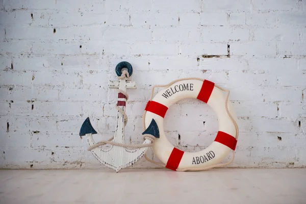 Eine Komposition über ein Meeresthema mit Anker und Rettungsring an einer weißen Ziegelwand. — Stockfoto