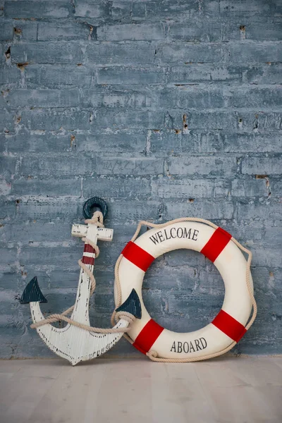 A composition on a sea theme with an anchor and life ring on a gray brick wall. — Stock Photo, Image