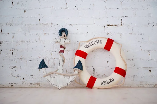 Eine Komposition über ein Meeresthema mit Anker und Rettungsring an einer weißen Ziegelwand. — Stockfoto