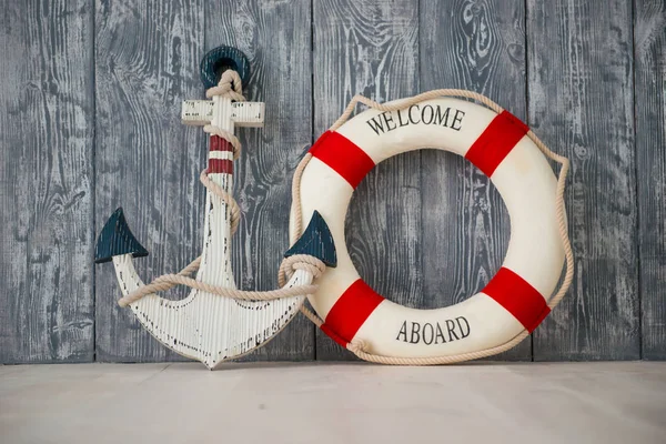 Композиция на морскую тематику с якорем и спасательным канатом на деревянном фоне — стоковое фото