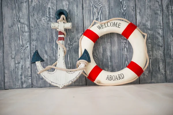 Композиция на морскую тематику с якорем и спасательным канатом на деревянном фоне — стоковое фото