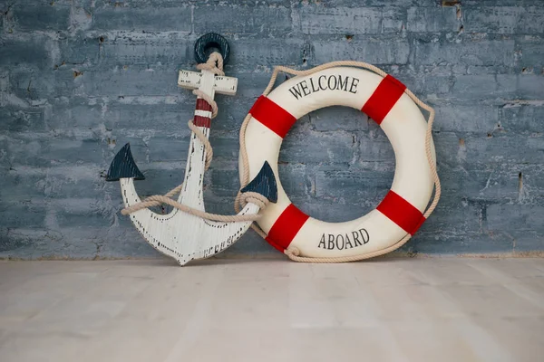 Composition on a sea theme with an anchor and life ring on a gray brick wall. — Stock Photo, Image