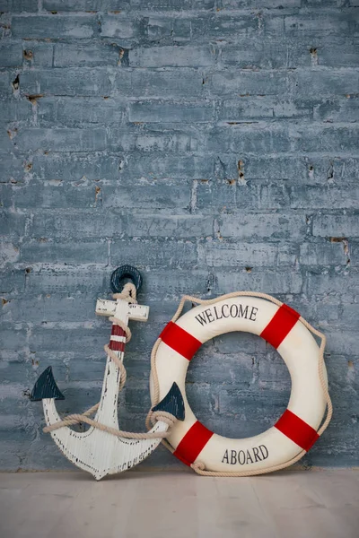 Komposition über ein Meeresthema mit Anker und Rettungsring an einer grauen Ziegelwand. — Stockfoto