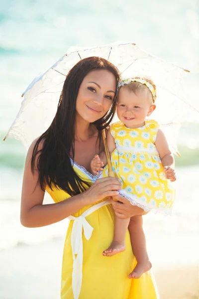 Anya és lánya egy forró napon egy fehér csipke napernyő alatt — Stock Fotó