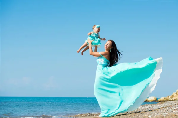 Anne ve çocuk kumsalda oynarken. Anne bebeği atar. — Stok fotoğraf