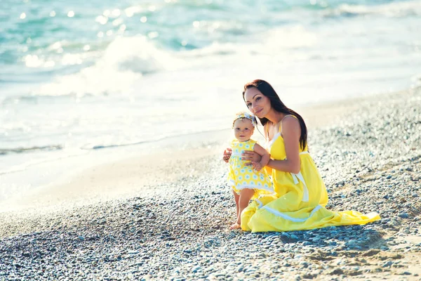 Glückliche Familie in einem gelben Kleid. Mutter und Kind spazieren am Strand — Stockfoto