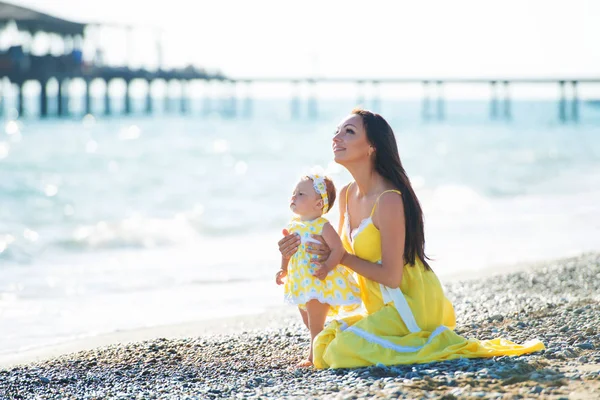 Sarı elbiseli mutlu bir aile. Anne ve çocuk sahilde yürüyor — Stok fotoğraf