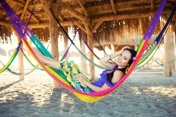 Pretty amazing cheerful young girl on the beach, lying in a hammock and smiling in a black sexy bikini in a wide luxurious hat and mirrored sunglasses are reflected palm trees, lifestyle, tanned — Stock Photo, Image