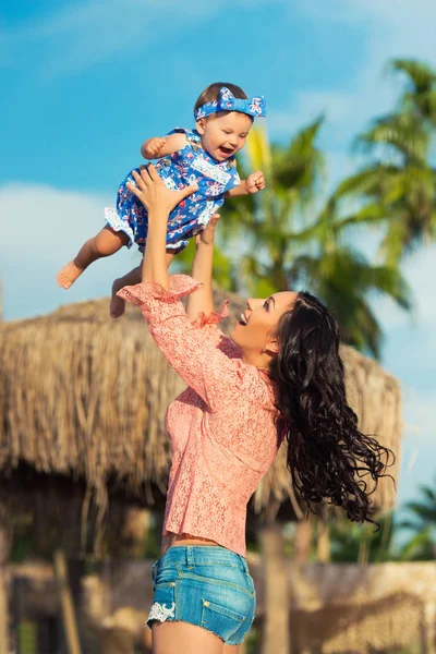 Mutter und Kind spielen am Strand. Mutter wirft das Baby hin. — Stockfoto