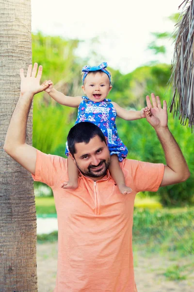 Linda menina está sentada com seu pai em seu pescoço — Fotografia de Stock