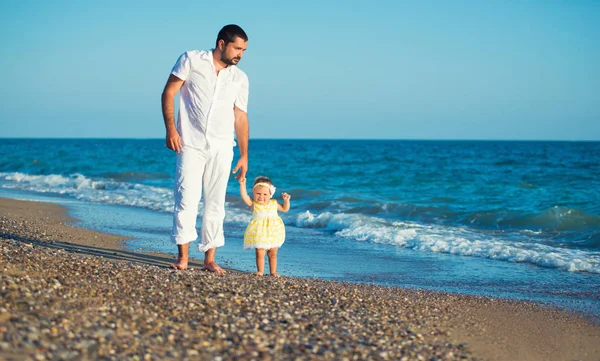 Glückliche Familie, Vater mit Tochter am Strand, lernt laufen. — Stockfoto