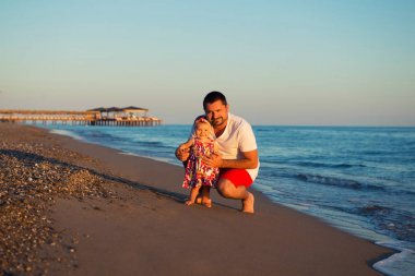 Küçük, tatlı kızınızı da kumsalda oynarken mutlu baba