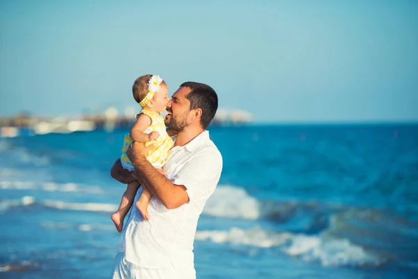 Eine glückliche Familie, Vater und Tochter spielen. eine kleine Tochter beißt ihrem Papa an die Nase. — Stockfoto