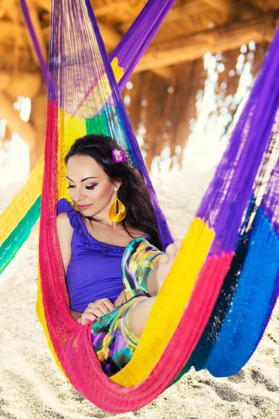 Abbastanza sorpreso allegra ragazza sulla spiaggia, sorridente si trova in un'amaca sullo sfondo di palme, stile di vita, abbronzato. Attività ricreative — Foto Stock