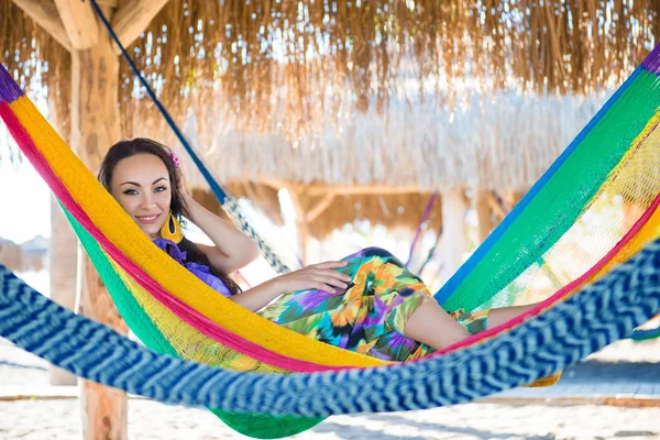 Pretty surprised cheerful young girl on the beach, smiling lies in a hammock against the backdrop of palm trees, lifestyle, tanned. Recreation — Stock Photo, Image