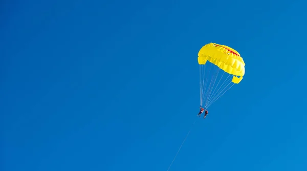 黄色のパラシュート飛行。笑顔でパラシュート。水の残りの部分します。空の旅。リゾートでのアクティブな時間。ビーチのエンターテインメント. — ストック写真