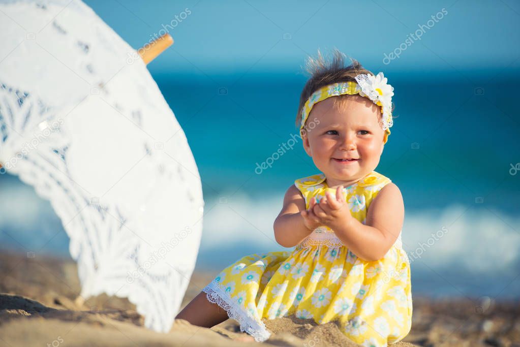 Lovely little girl on the beach with an umbrella
