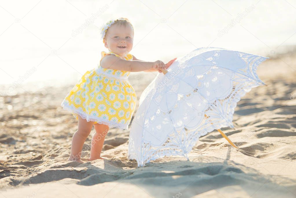 Lovely little girl on the beach with an umbrella