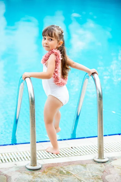 Young beautiful little girl in a bathing suit making water splash at the swimming pool.Enjoying summer and having fun. Vacation mood — Stock Photo, Image