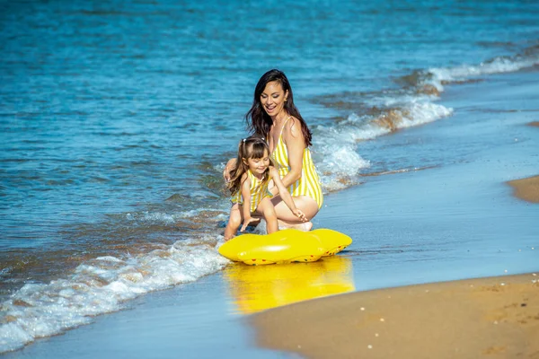 Mutlu bir anne ve gülümseyen bir çocuğu var. 3 yaşında, kumsalda, sıcak deniz dalgaları ve mavi gökyüzü olan bir kumsalda. — Stok fotoğraf