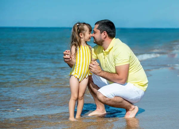 Baba ve küçük kız oynuyorlar, sahilde koşuyorlar ve deniz kıyısında oynuyorlar. Bir çocukla birlikte denizde aile tatili. — Stok fotoğraf