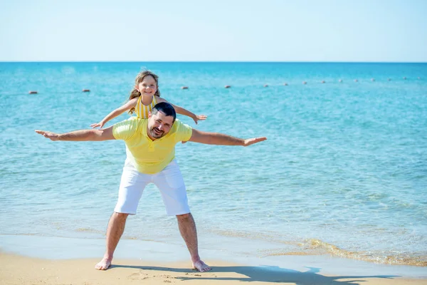 Táta a holčička si hrají, běhají po pláži a pohrávají si na mořském pobřeží. Rodinná dovolená na moři s dítětem — Stock fotografie