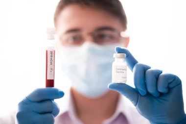Kan testi tüpü ve aşı erkek elinde, yakın plan, doktor maske takıyor. Aşı kavramı, Covid-19 koronavirüs teşhisi, grip virüsü tedavisi.
