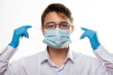 Corona virüsü covid-19: Gözlüklü ve tıbbi veya cerrahi maske takan genç bir doktorun yüzüne sahip.