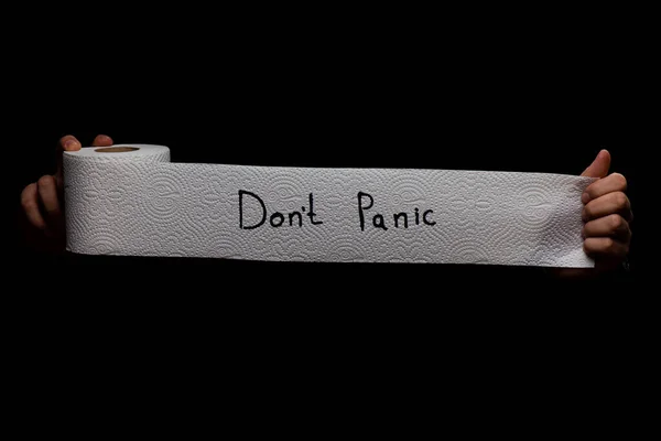 Panic buying Covid-19 Coronavirus outbreak concept. Roll of toilet paper with inscription Don\'t panic on black background.