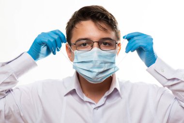 Corona virüsü covid-19: Gözlüklü ve tıbbi veya cerrahi maske takan genç bir doktorun yüzüne sahip.