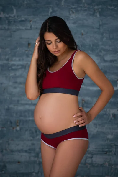 Gri Tuğlalı Bir Duvarın Arkasında Spor Çamaşırlı Güzel Hamile Genç — Stok fotoğraf