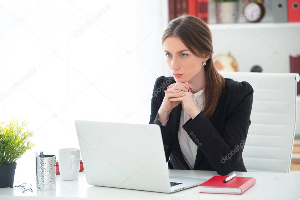 Young woman working at a desk with a laptop in an office. Female business, distant work.