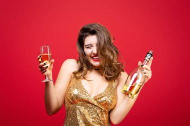 Kırmızı rujlu, altın rengi elbiseli ve elinde şampanya olan seksi bir kadın. Yeni yıl tatili kavramı, doğum günü partisi.