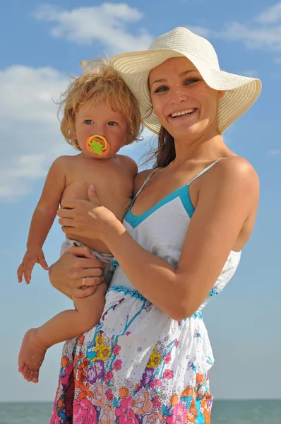 Jonge moeder met baby op het strand Stockfoto