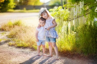 Çocuklar çiçekli wisteria arka plan karşı sarılmak