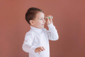 egy kisfiú kezében tart egy dollárt rózsaszín alapon, az első kereset öröme, egy jó hozzájárulás a gyermeknek a jövőre nézve