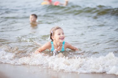 Denizde yüzen turkuazlı bir kız, denizde yüzen mutlu çocuklar, denizde yüzen dalgalar, suda yüzen mutluluklar.