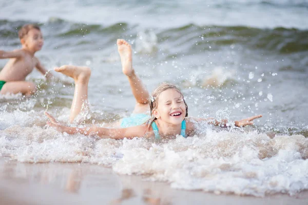 Girl in a turquoise bathing suit in the sea, happy children swimming in the sea, waves and splashes from swimming in the sea, happiness from swimming in the water