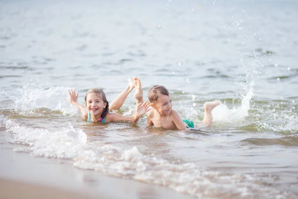 happy children swimming in the sea, waves and splashes from swimming in the sea, happiness from swimming in the water