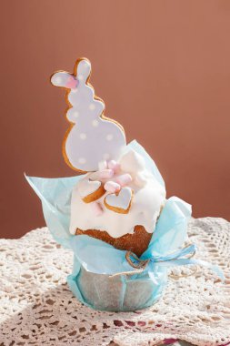 Easter cupcake decorated with cookies in the form of hearts and an Easter bunny with delicate blue packaging on a pink background