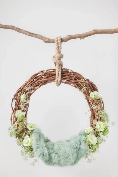 Yeşil çiçeklerle süslenmiş bir çubukta asılı üzüm beşiği yüzüğü ve yeni doğan bebekleri ve çocukları vurmak için yeşil yün bir halı, fotoğraf çekimi için fikir.