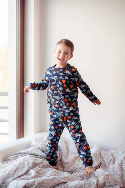 Ένα Αγόρι Πιτζάμες Διαστημικές Ζωγραφιές Πηδάει Στο Κρεβάτι Πρωινές Ασκήσεις — Φωτογραφία Αρχείου