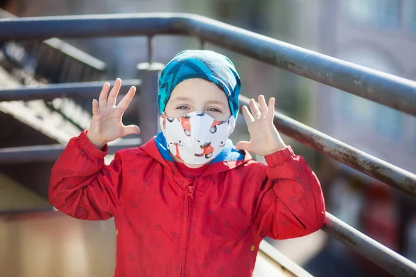 Çocuğun yüzünde mopet desenli kumaştan yapılmış tıbbi maske, virüslere karşı koruma, koronavirüs.