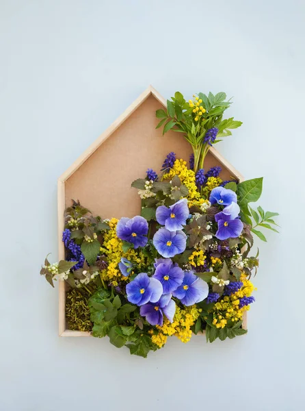 Çiçekler, nonoşlar ve diğer sarı ve mor kır çiçekleriyle süslenmiş ahşap bir çerçeve, gri arka planda bir çiçek resmi