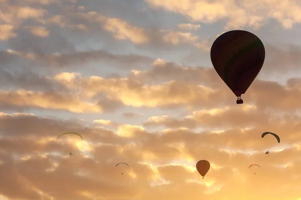 Σιλουέτα Θερμού Αέρα Ballon Και Αλεξίπτωτο Που Φέρουν Στο Ηλιοβασίλεμα — Φωτογραφία Αρχείου