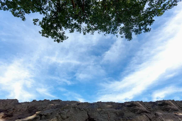 Błękitne Niebo Chmurami Dla Tekstury Tła Skałą Drzewami Pierwszego Planu — Zdjęcie stockowe