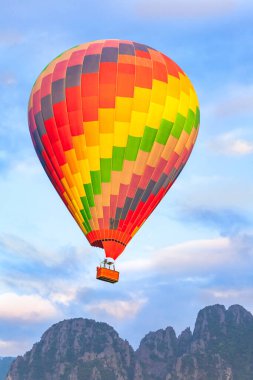 Renkli sıcak hava balonu gün doğumunda orman ve dağın üzerinde uçuyor.