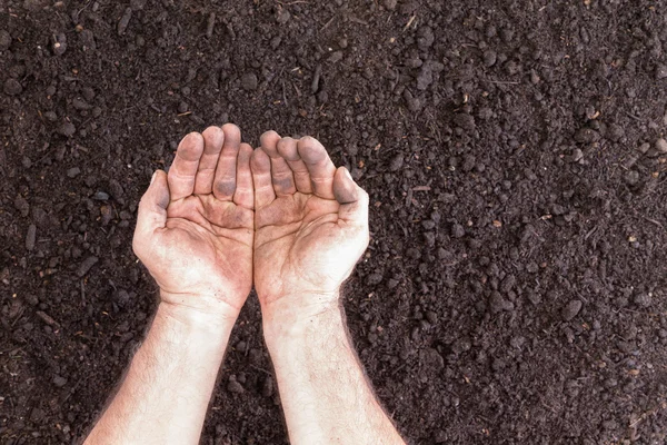 Pair of empty hands holding nothing over bare soil — Stock Photo, Image