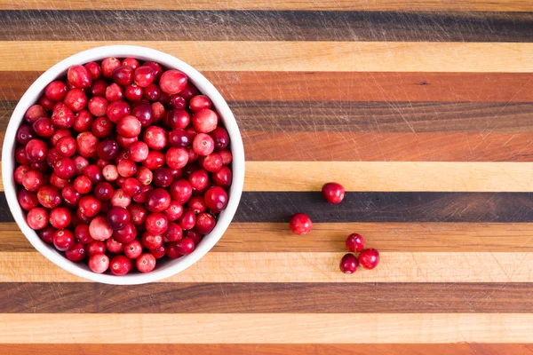 Bowl of fresh ripe cranberries on a cutting board — Stock Photo, Image